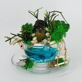 Mini florarium composition in a mug with an artificial pond