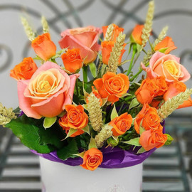 Bright composition of spray roses with wheat in a hatbox