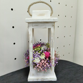 Composition in a wooden lantern with flowers