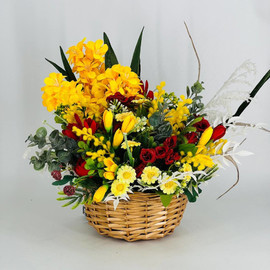 Arrangement of artificial flowers in a wicker basket as a gift for Easter