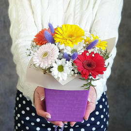 Bright composition in a small box of minigerberas, gypsophila and chrysanthemums