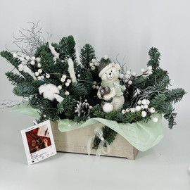 Buket iz vetok hvoi nobilis na stol s figurkoj "Medvezhonok v shapke"